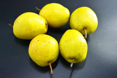 Bright tasty juicy pears of green, red and yellow color are located on a black plastic background....