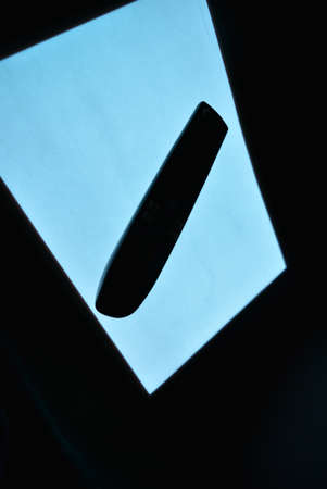 Luminous A4 paper with an electroluminescent coating is arranged in different planes on a pristine glossy surface with a female hand and a remote control. Excellent color background, color substrate,の写真素材