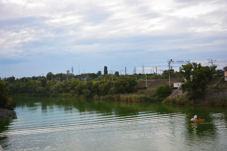 Small natural Lake Pishchevoye with green hills, unusual trees, reeds and vegetation in the area of...