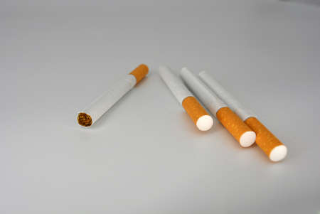 Many white cigarettes with a brown filter chaotic arranged on a white background. Smoking is blicking bad on health. Cigarettes worsen the work of the brain nervesの写真素材