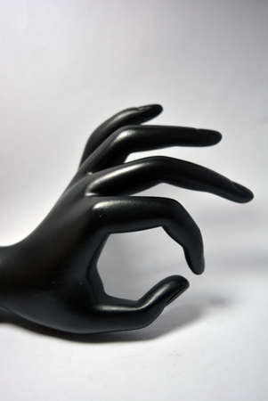 Ceramic, clay female hand covered with black matte paint is located on a white background.の写真素材