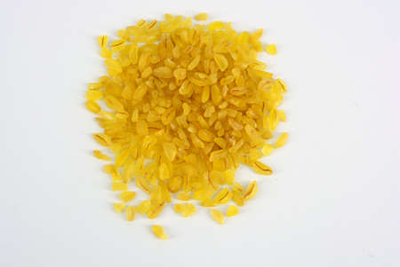 Fresh grains, cereals, yellow Bulgur scattered in plastic container and white background with interesting lighting.の写真素材