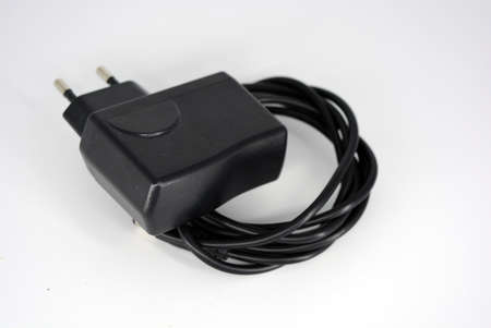 Black metal plug, power supply for connecting and charging the phone into a reinstate 220 in a white...