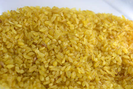 Fresh grains, cereals, yellow Bulgur scattered in plastic container and white background with...