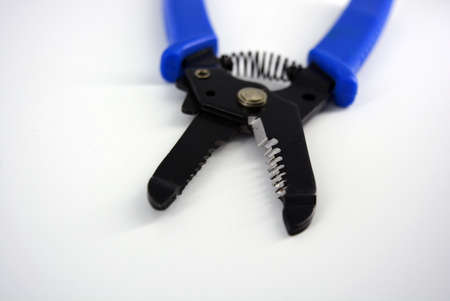 Metal plassentes with blue plastics handles for trimming wires of different diameter located on a white plastic background.の写真素材
