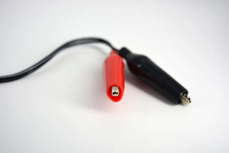 Black wire with red and black insulation, rubber and metal crocodiles for lining to the wire located on a white background.の写真素材