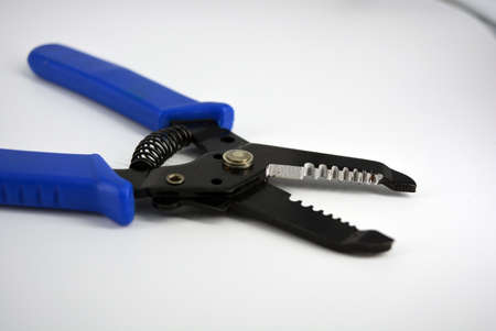 Metal plassentes with blue plastics handles for trimming wires of different diameter located on a white plastic background.の写真素材