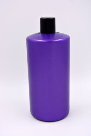 A large purple plastic round shampoo bottle with a black lid located on a white background.の写真素材