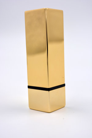 Beautiful, expensive gold women's lipstick plum, pink, red color with a gold cap is located on a white background.の写真素材