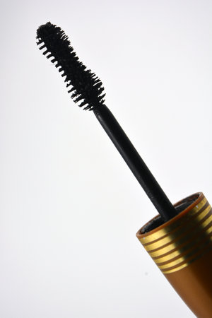 Decorative cosmetics, personal care products, women's black mascara with a gold cap, in gold packaging is located on a white background.の写真素材