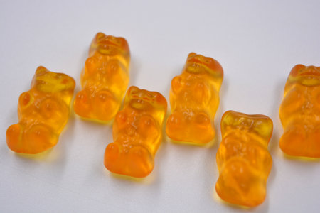 Bright children's orange chewing, jelly candies in the form and in the form of colored bears are located on a white background. Orange gummy bears on a white background. Close-up.の写真素材
