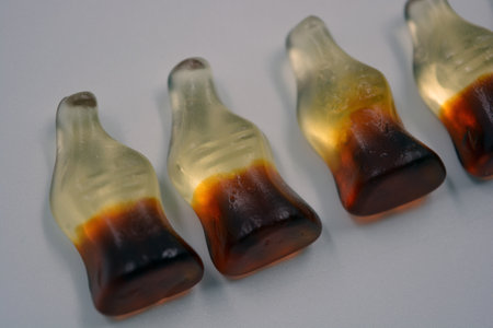 Bright children's chewing, jelly sweets in the form of drinks, bottles of cola are located on a white background. Close-up of caramel candies in row on white background.の写真素材