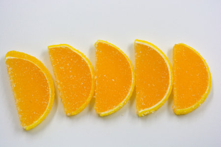 Yellow jelly sweets made in the form of sliced orange slices, lemon, fruits located in plastic transparent containers and sprinkled with sugar.の写真素材