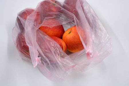 A large package of fruit, healthy food, a lot of red, ripe apples lie in a pink disposable bag. Red apples in a plastic bag on a white background. Isolatedの写真素材