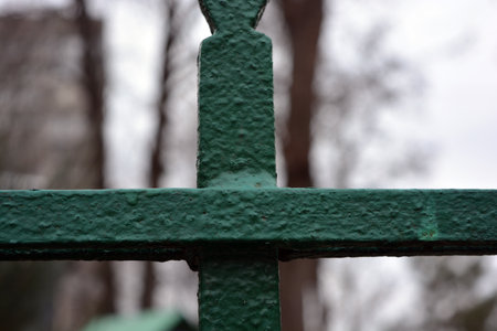 An old Soviet metal fence welded with an interesting shape, arrows and circles, painted with green paint. A fragment of a fence in the park. Close-up.の写真素材