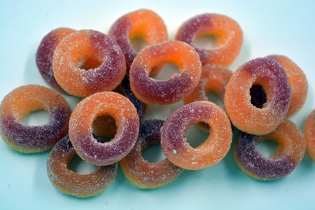 Beautiful and bright colored sweets in the form of orange and red donuts in sugar powder. Colorful...