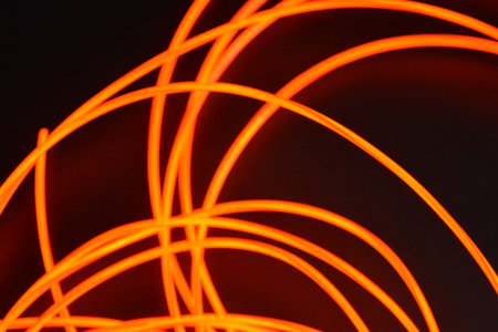 Abstract light painting in red and orange colors on a black. Unusual glowing background of chaotically stacked thin light wires, red glowing tourniquet, illuminated, thin wire.の写真素材