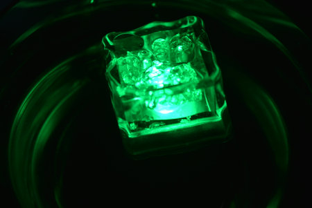 Beautiful, stylish photo of parties, celebrations, one glass champagne glass with glowing plastic ice cubes in drinks that glow green light.の写真素材