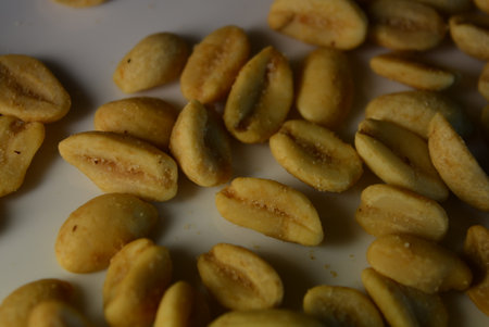 Roasted coffee beans on a white plate. Close-up. Healthy foods, health, nuts, salted toasted peanuts...