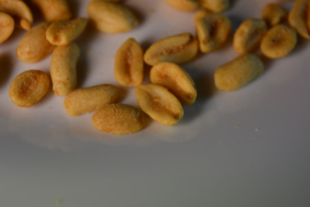 Close up of roasted peanuts on a white plate with copy space. Healthy foods, health, nuts, salted...