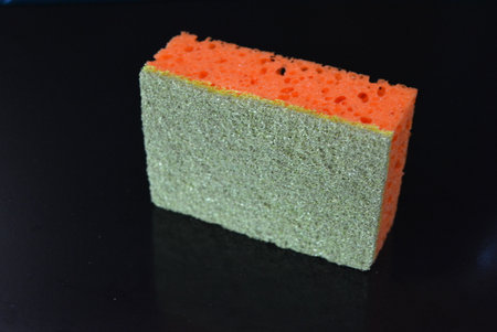 Sponge for cleaning the house on a black background close-up. Things that are often used in the...