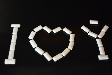 I love you written on a black background with white marshmallows. Food, personal care products, product, chewing gum, white chewing pillows, chewing gum arranged on a black.の写真素材