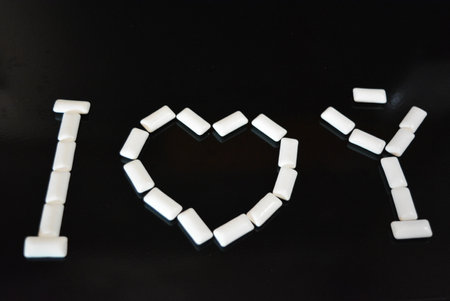 I love you spelled with white marshmallows on a black background. Food, personal care products, product, chewing gum, white chewing pillows, chewing gum arranged on a black.の写真素材
