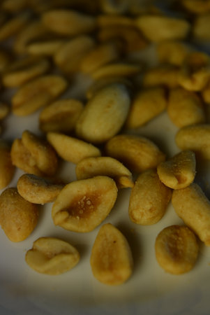 Roasted salted peanuts on a white plate close-up. Healthy foods, health, nuts, salted toasted peanuts are arranged interestingly on a white glass plate.の写真素材