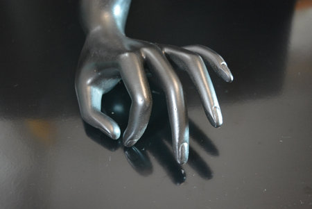 Hand of a mannequin on a black background, closeup of photo. A matte black ceramic hand-shaped statuette is located on a matte black background.の写真素材
