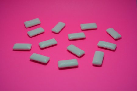 White chewing gums on pink background. Top view. Flat lay. On the charcoal, peach paper are white cushions from chewing gum.の写真素材