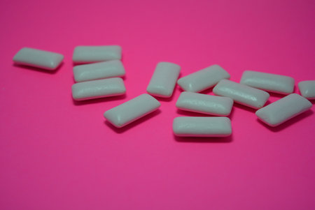 White chewing gums on a pink background. Close-up. On the charcoal, peach paper are white cushions from chewing gum.の写真素材