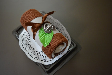 Chocolate cake with green leaf on top on the cake stand. Brown face towel rolled into a tube with heart and love.の写真素材