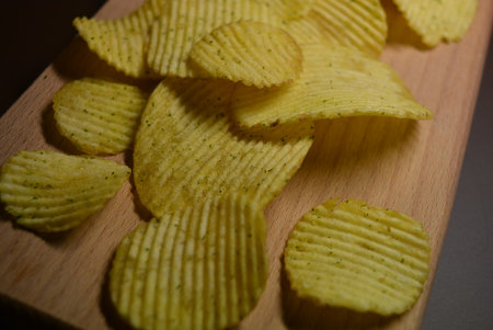 Potatoes fried wavy, embossed, potato chips with sour cream and greens, facies on a wooden board.の写真素材