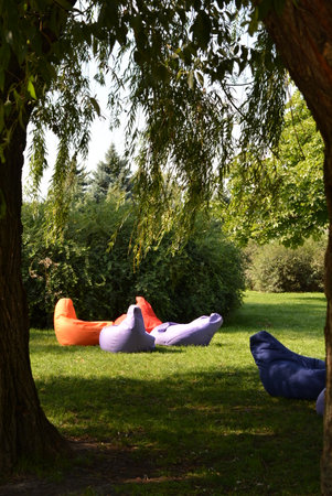 The recreation area, on the green lawn among green trees and bushes, are multi-colored pillows for rest and relaxation in the sun and in the shade.の写真素材