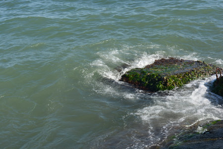 Rocky coast of the Black Sea with waves breaking on it. Unusual color of the black sea with a large...