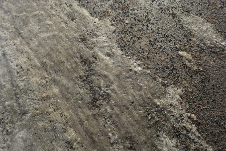 Background texture of asphalt, the surface of the asphalt is covered with cracks. Ice, frozen water...