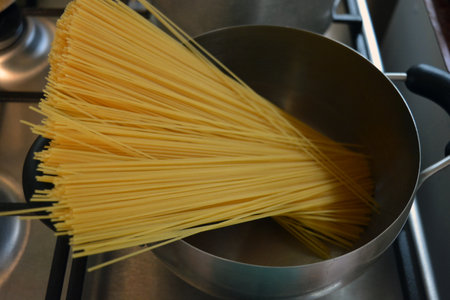 Close up of spaghetti in a stainless steel pot on a gas stove. Long Italian durum wheat vermicelli is boiled with hot water in a gray metal saucepan on a gas stove.の写真素材