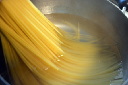 Pasta cooking in a pot, close-up of the spaghetti. Long Italian durum wheat vermicelli is boiled with hot water in a gray metal saucepan on a gas stove.の写真素材