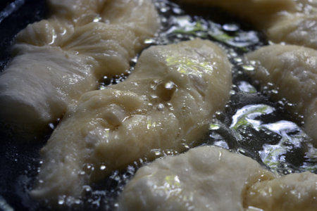 Fried dumplings in a frying pan, close-up. Ukrainian national cuisine, fried verguntsi in hot sunflower oil in a black metal frying pan.の写真素材