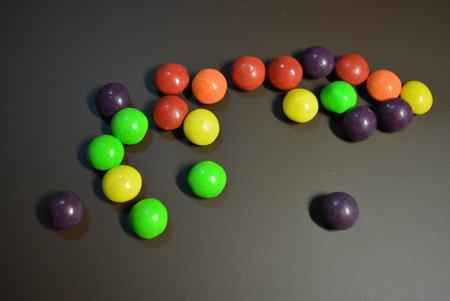 Colorful candies on a black background, closeup of photo. Beautiful bright small colored round...