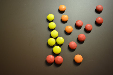 Colorful candies on a black background, closeup of photo. Beautiful bright small colored round...