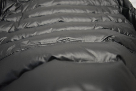 Clothing, outerwear, everyday women's clothes. Beautiful stylish black women short down jacket with white fluffy puffer jacket hanging on gray stone background.の写真素材