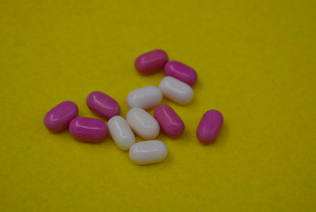 Pink and white candies on a yellow background. Close up.
