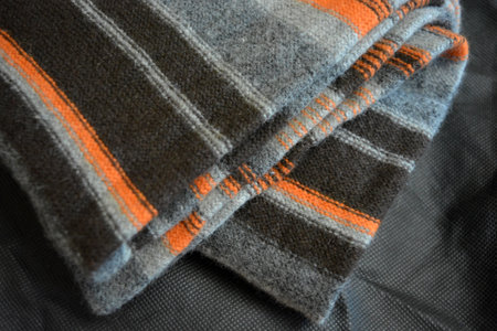 Close up of black and orange checkered woolen fabric. A men's sweater is made in the form of orange, gray, dark gray, black stripes, which is woven from natural wool yarn.の写真素材