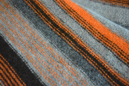 Striped fabric texture, close up of woolen fabric texture background. A men's sweater is made in the form of orange, gray, dark gray, black stripes, which is woven from wool yarn.の写真素材