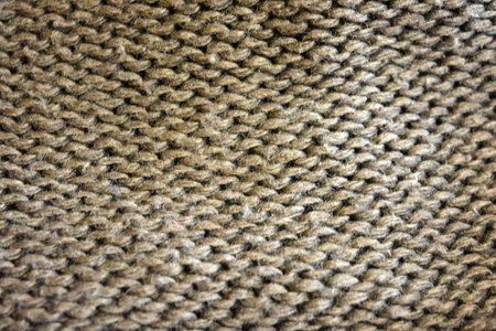 Woolen knitted fabric as a background. Close-up. Women's clothing, stylish knitwear made of natural...