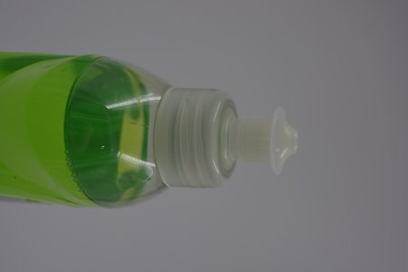 Green bottle of liquid soap on a white background. Close-up. A transparent bottle with a plastic...