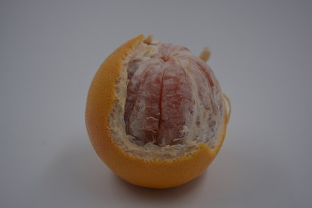 Grapefruit on a white background. Citrus on a white background. One peeled orange-red grapefruit...