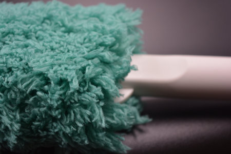 Close up of a green scrubber. Shallow depth of field. Green soft fluffy, nylon, synthetic fabric with white plastic base, handle for cleaning the room.の写真素材