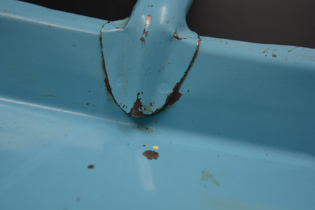 Close up of blue dustbin with rust and dirt on it. A blue metal scoop from which the paint has come off is located on a black matte background.の写真素材